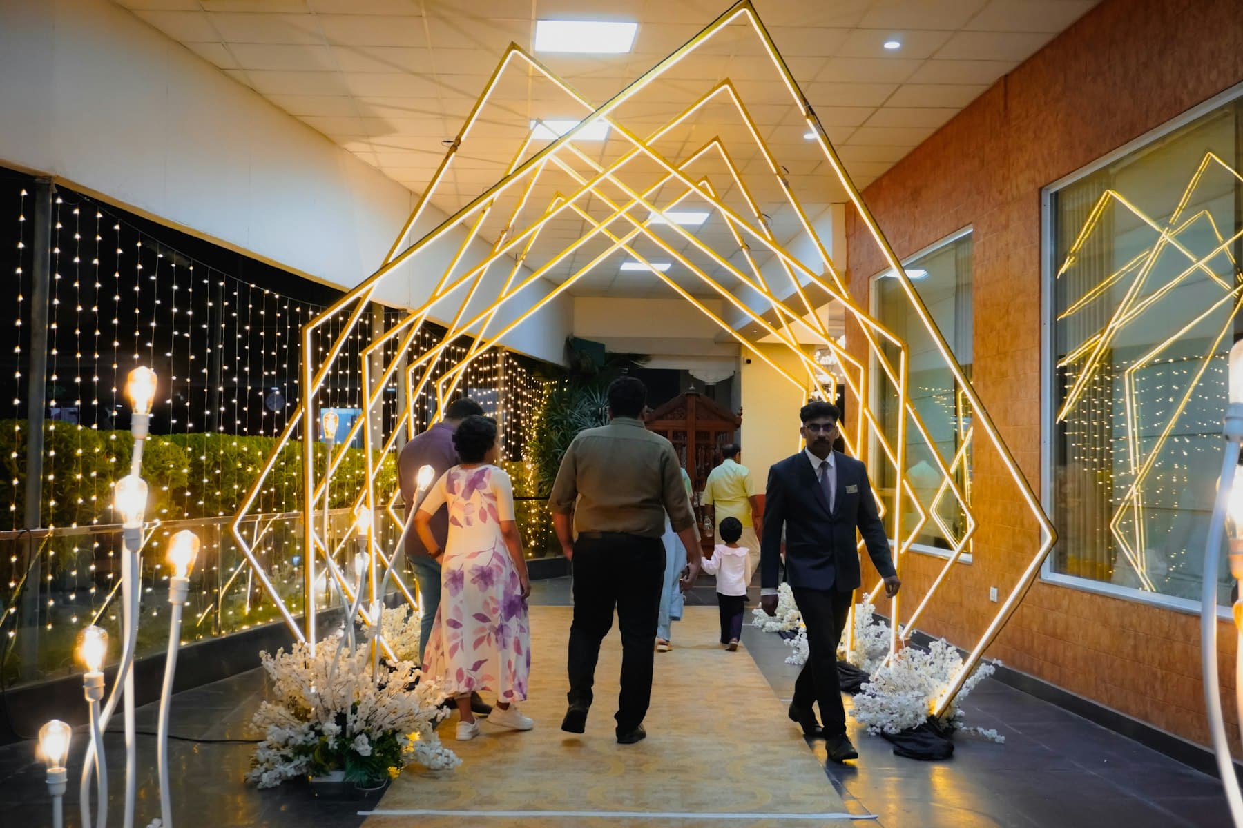 Guests walking through an illuminated geometric archway at an event