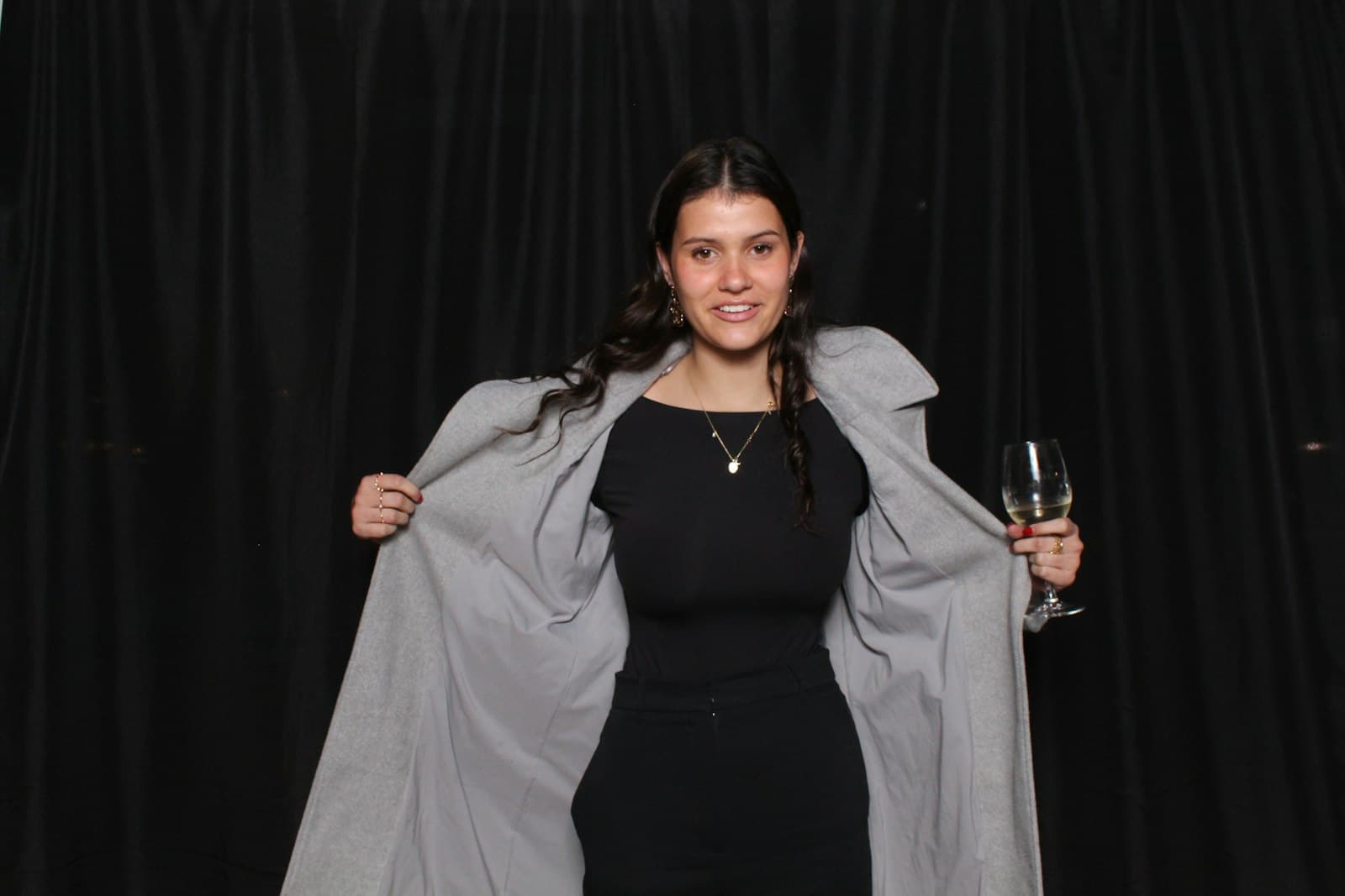 Guest posing with a glass in front of a black velvet backdrop